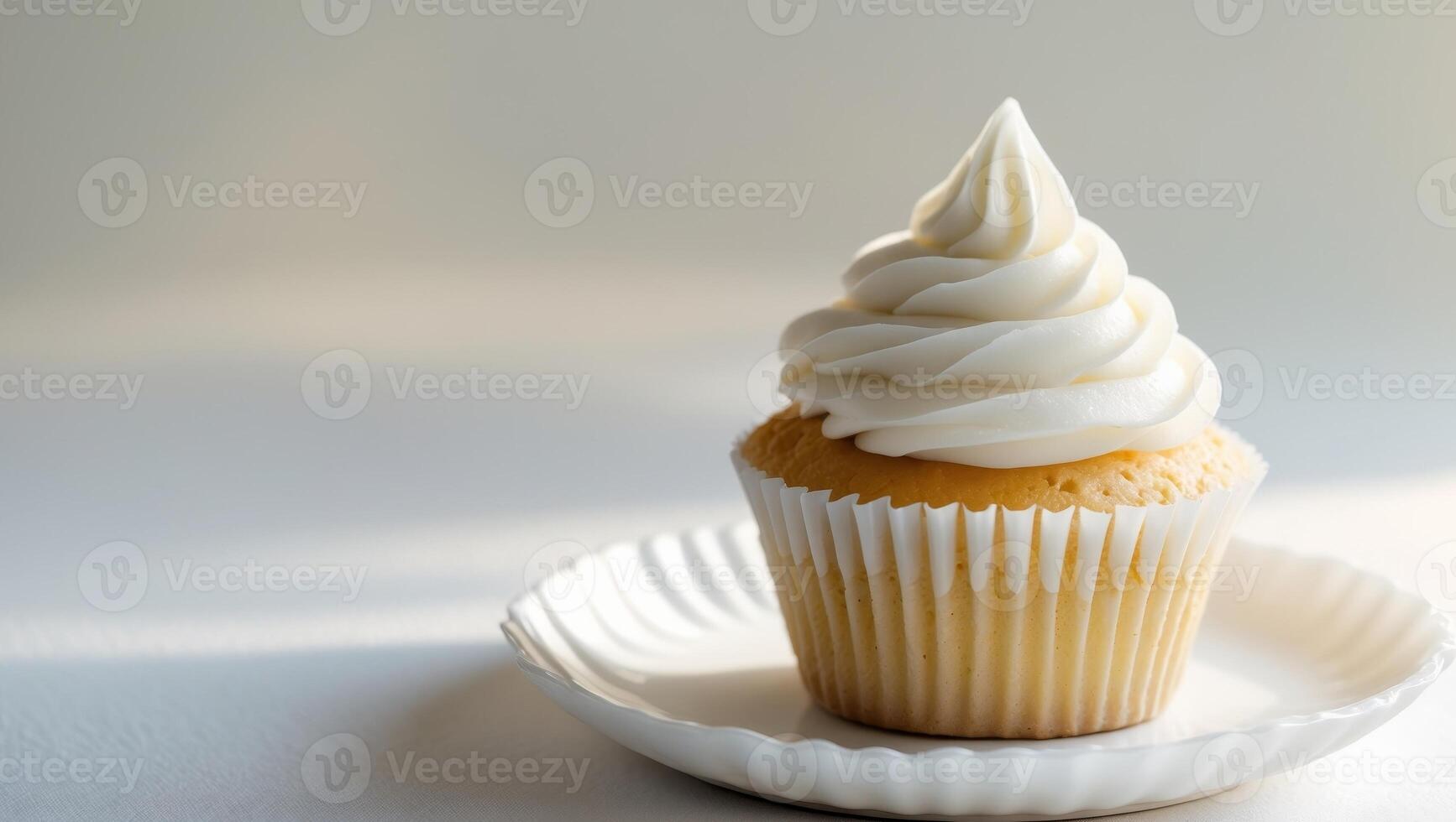A cupcake with white frosting on a white plate photo
