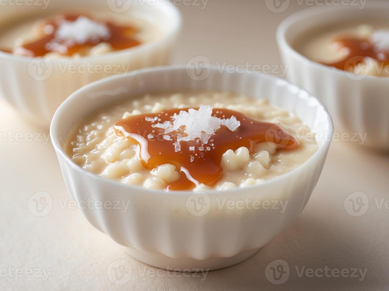 Creamy rice pudding dessert with caramel sauce and sea salt topping in white cups photo