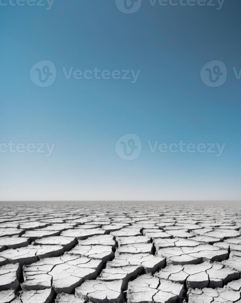 Dry cracked earth showcases the impact of drought in a parched landscape under a clear blue sky photo