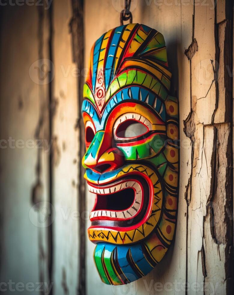 Colorful tiki mask hanging on a weathered wooden wall photo
