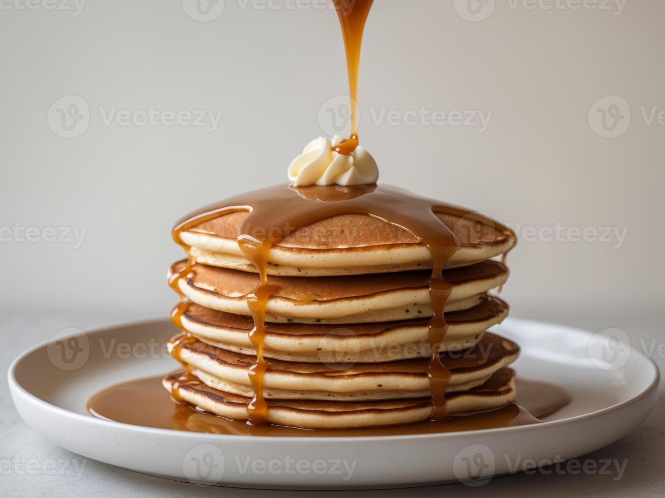 A stack of pancakes with syrup being poured over them photo