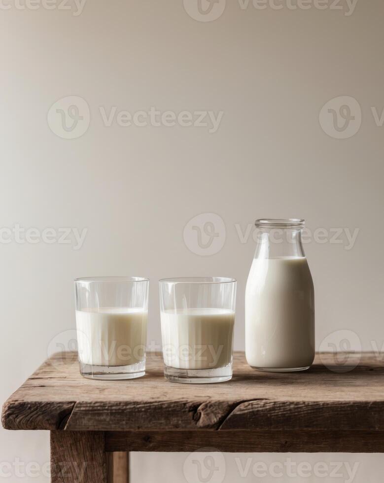 three glasses of milk and a bottle of milk on a wooden table photo