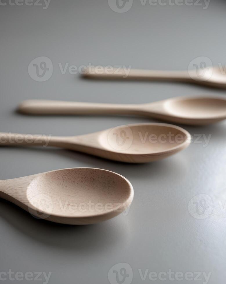 three wooden spoons are lined up on a gray surface photo