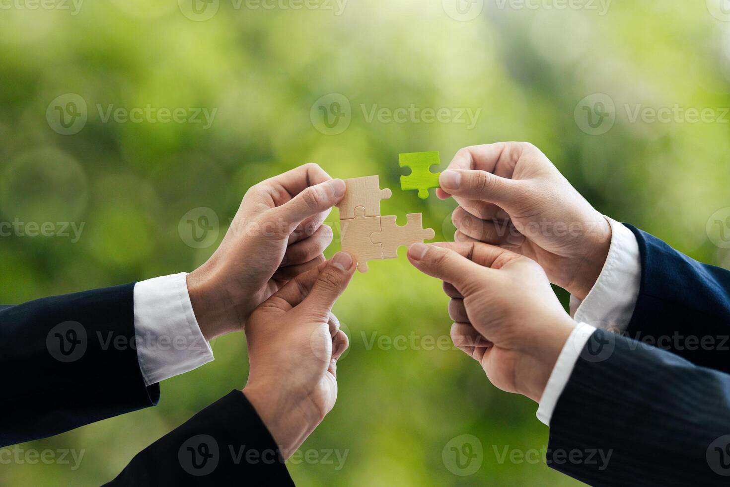 Office workers holding a jigsaw puzzle, teamwork and unity. Charity, volunteering, problem solving, business unity, business teamwork, success and strategy. Green background. photo