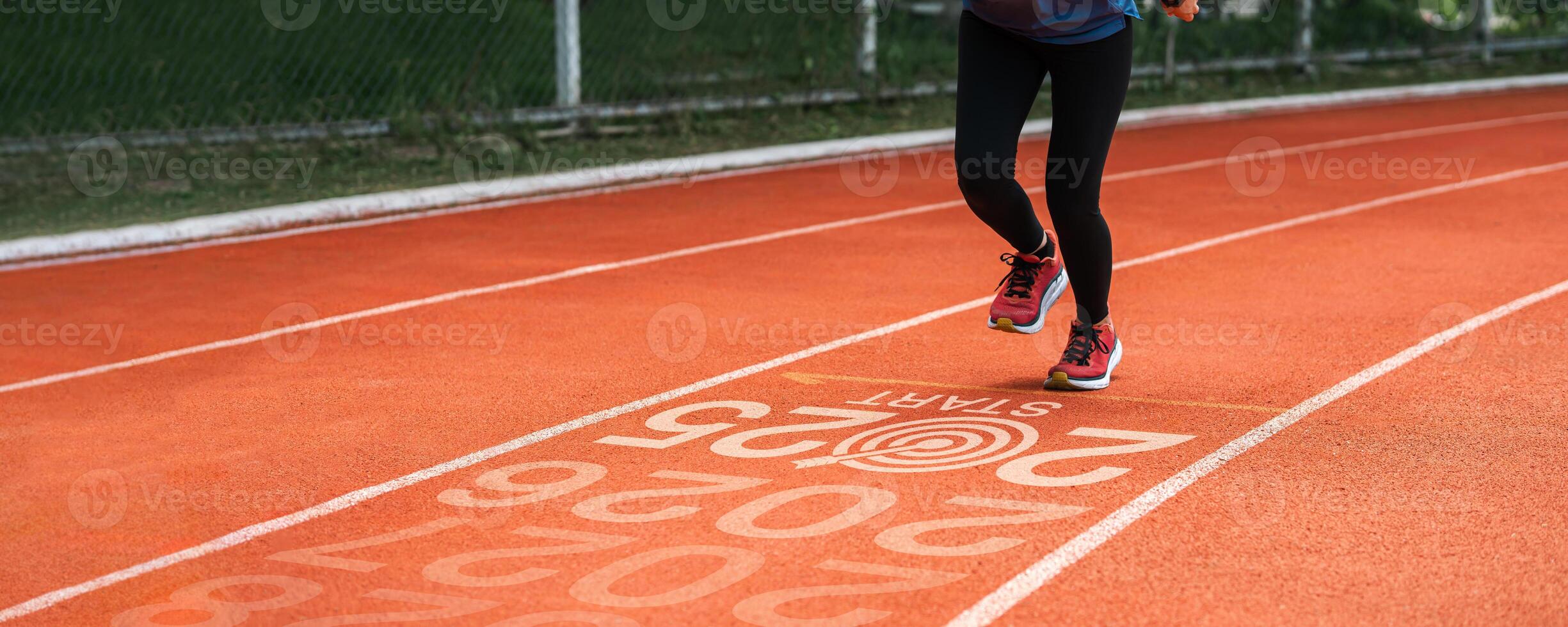 New year 2025 concept, beginning of success. Text 2025 written on asphalt road and male runner preparing for the new year. Concept of challenge or career path and change. photo