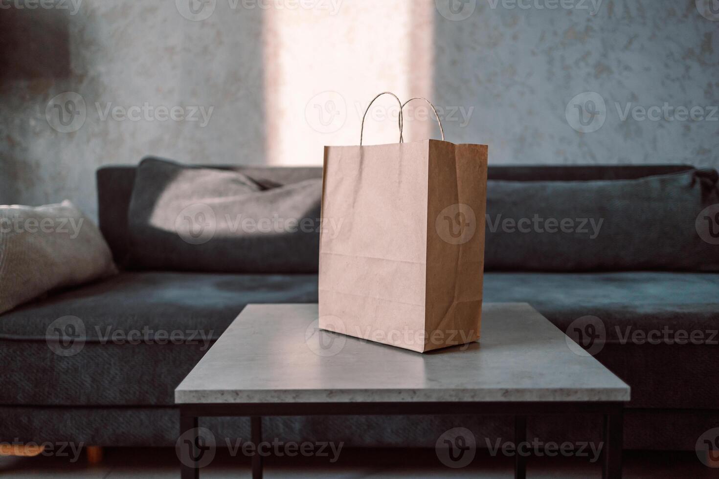 Disposable bag of kraft paper with products left by courier of food delivery service on a table at home. Copy space. Kraft design. photo
