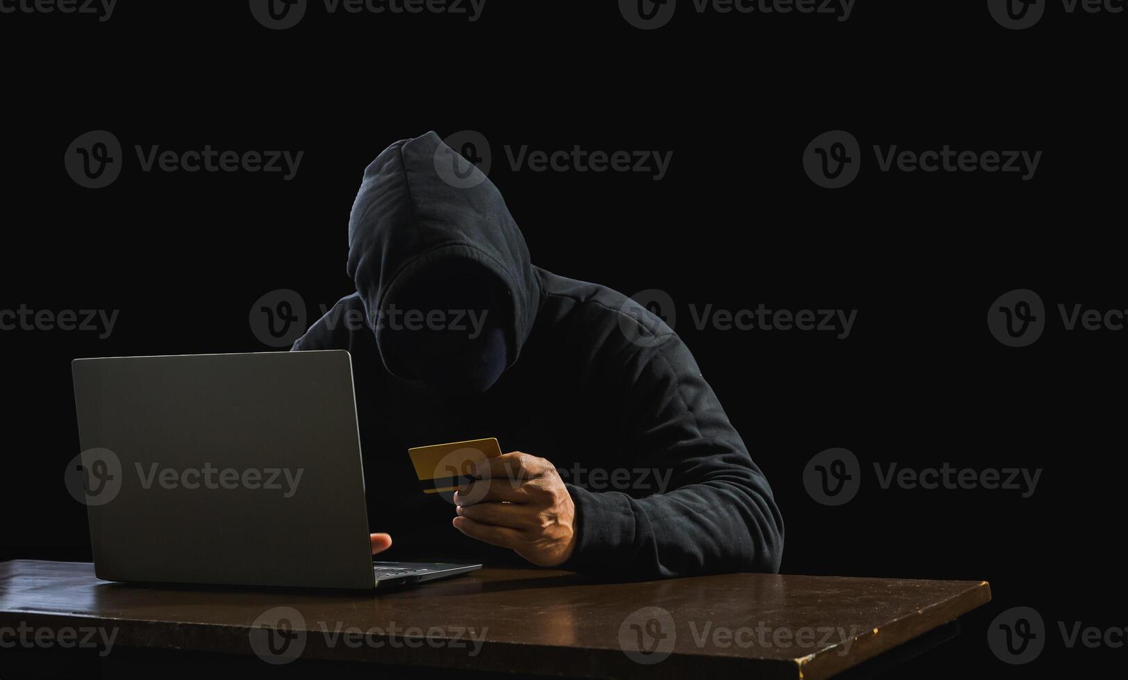 Portrait hacker spy man one person in black hoodie sitting on table looking computer laptop used login password attack security to data digital internet network system night dark background copy space photo