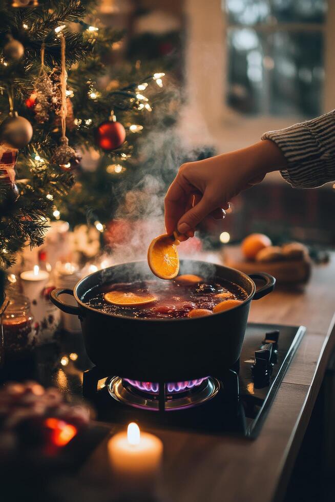 Festive holiday beverage preparation with spices and citrus near a decorated Christmas tree photo