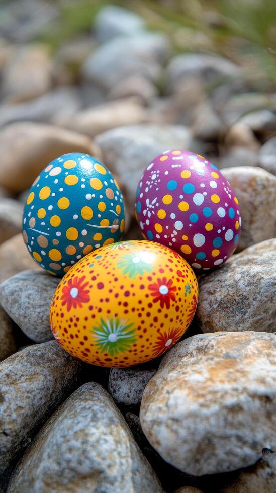 Colorful decorative eggs resting on pebbles in a natural setting during springtime photo