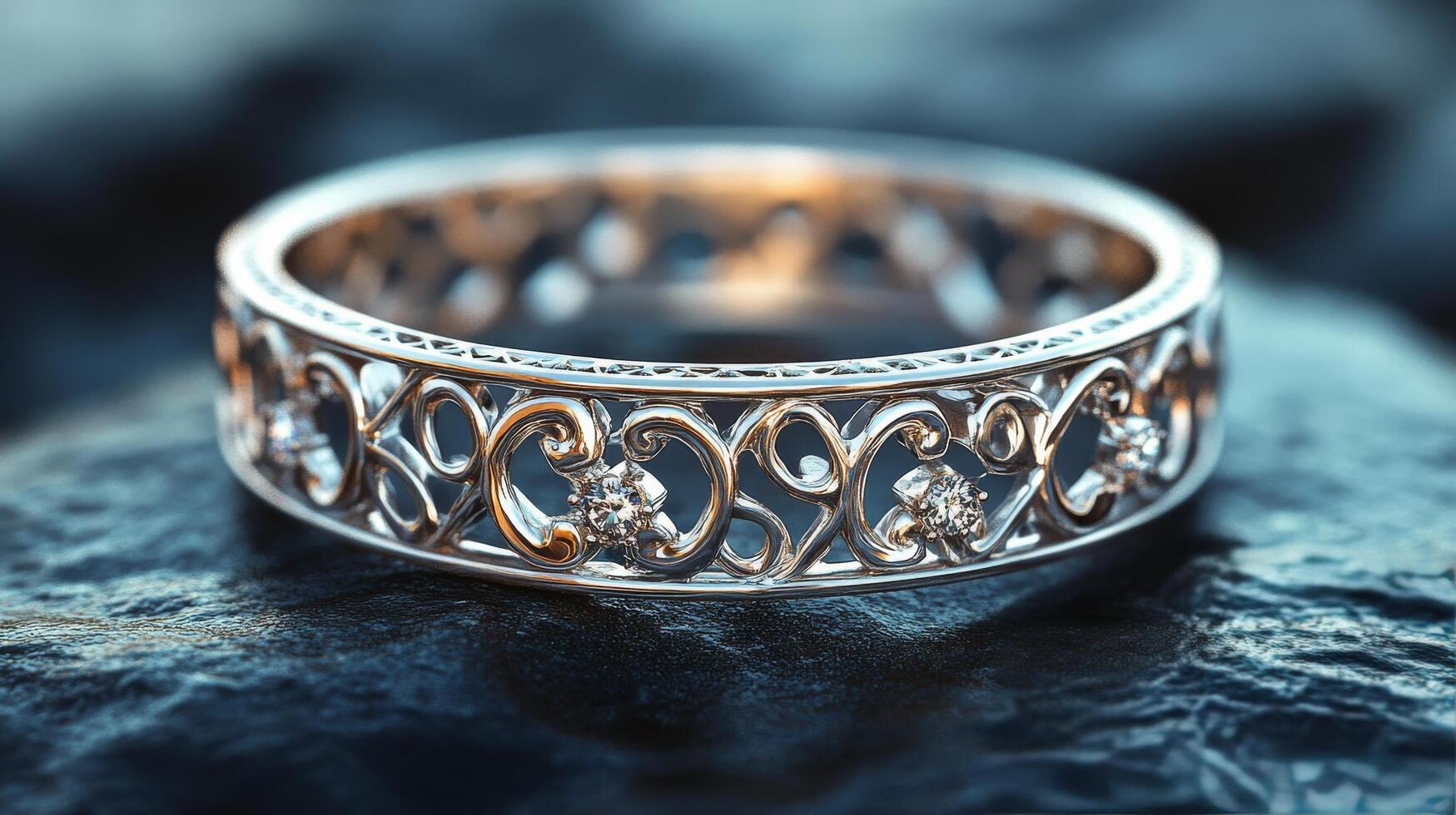 Intricate silver ring with floral motifs displayed on a textured stone surface photo