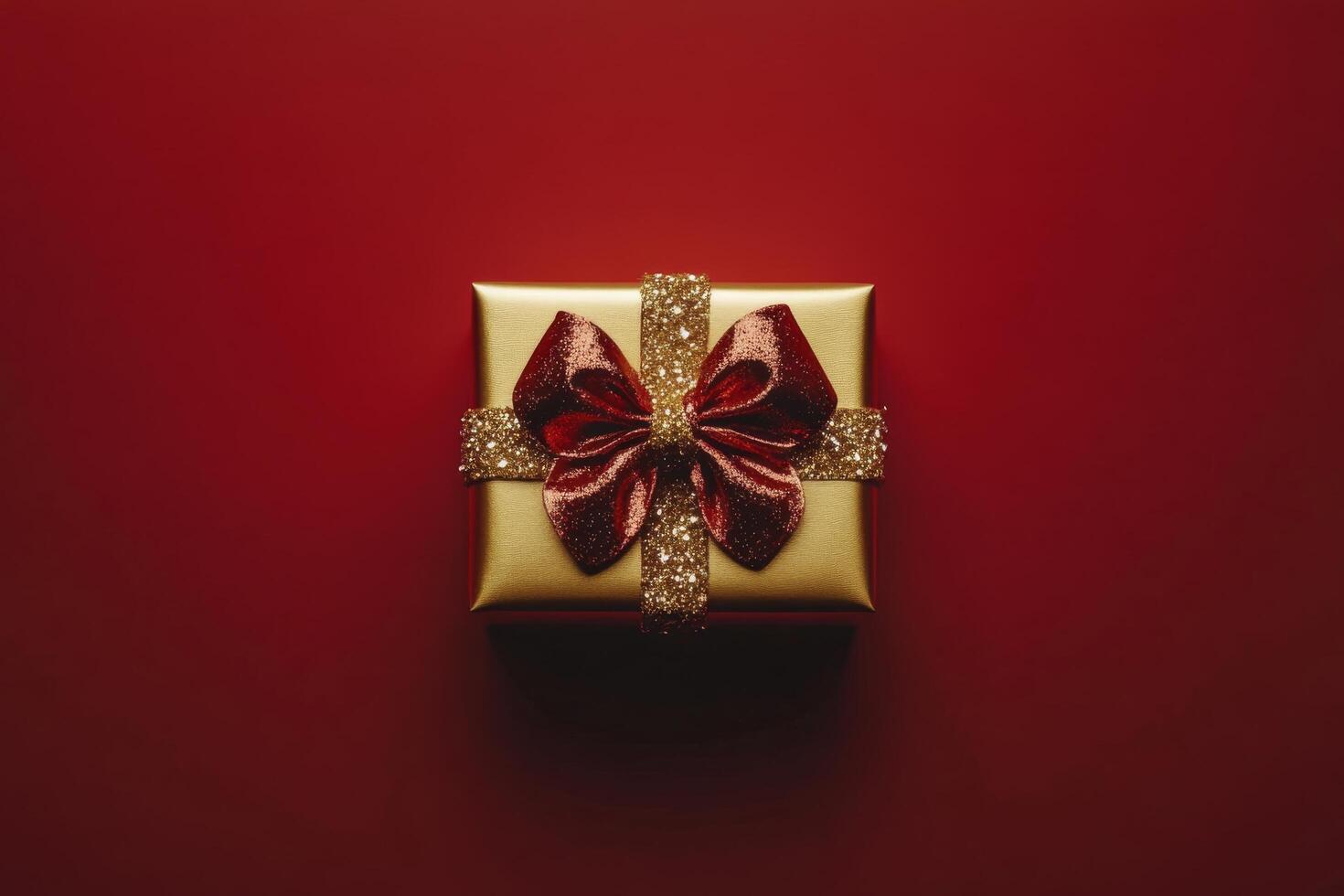 Shimmering gold gift box with red ribbon on vibrant red background ready for a special occasion photo