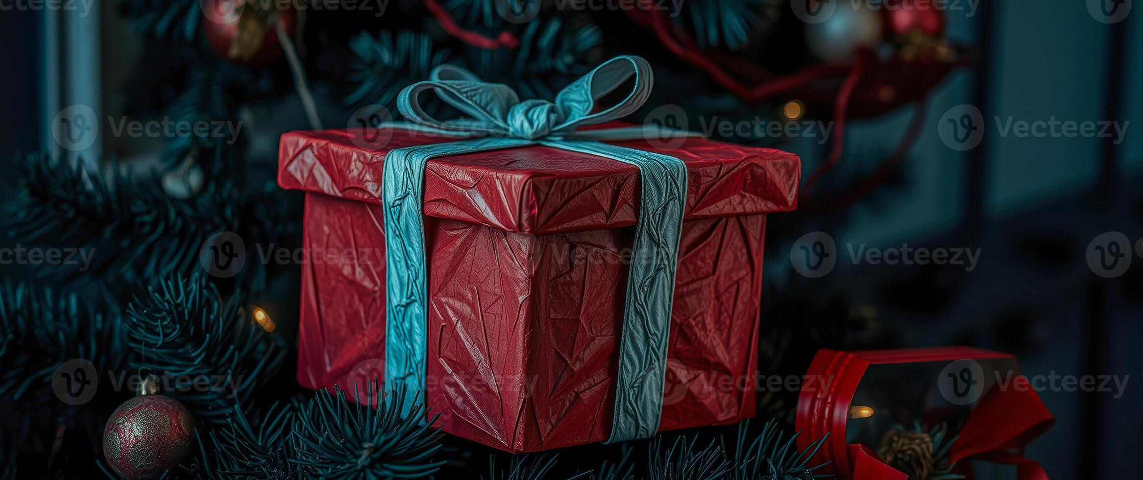 red gift box with teal ribbon on artificial tree photo