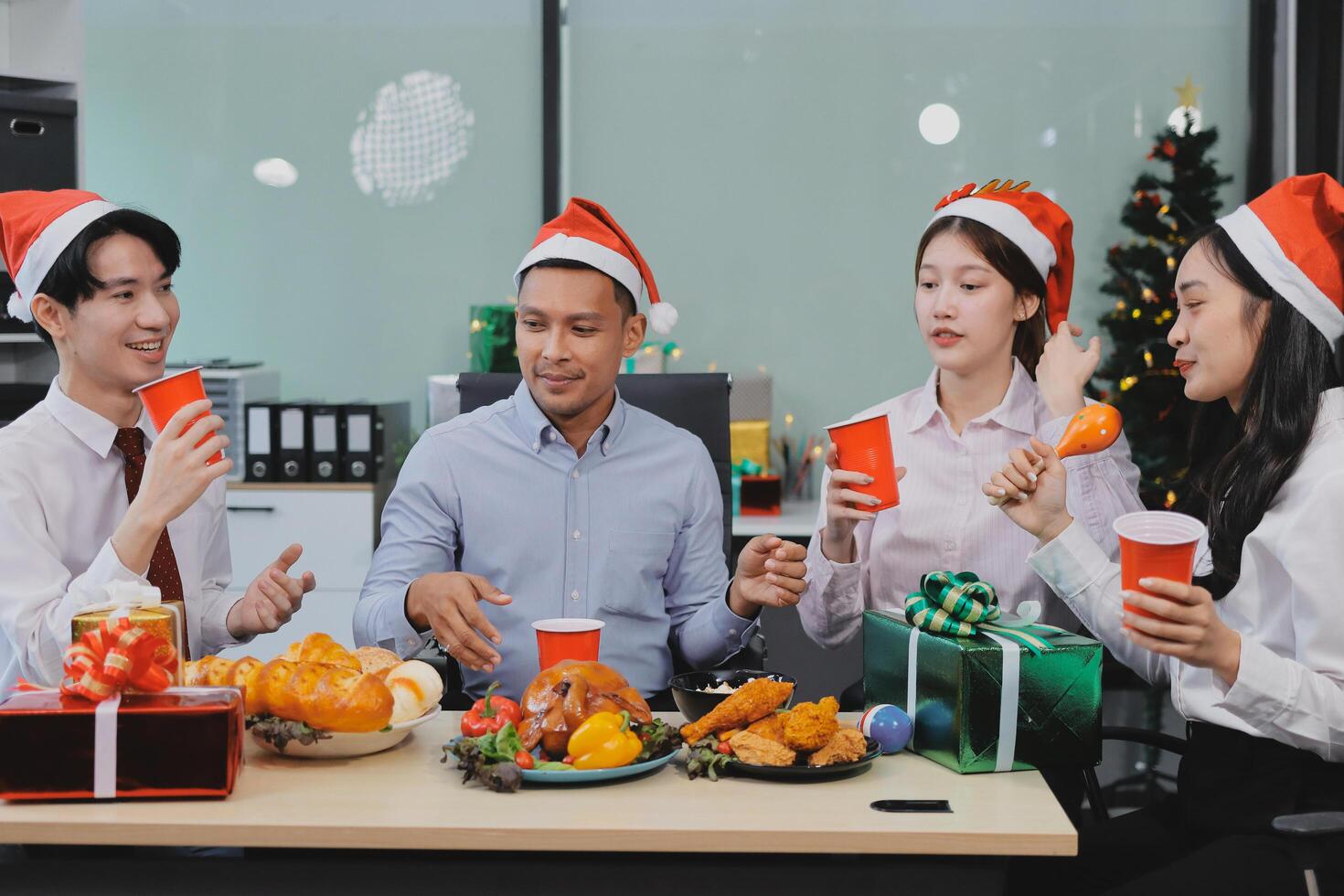 full length view of a group of business team wearing red Santa hat and exchange gift box together in the office for Christmas. photo
