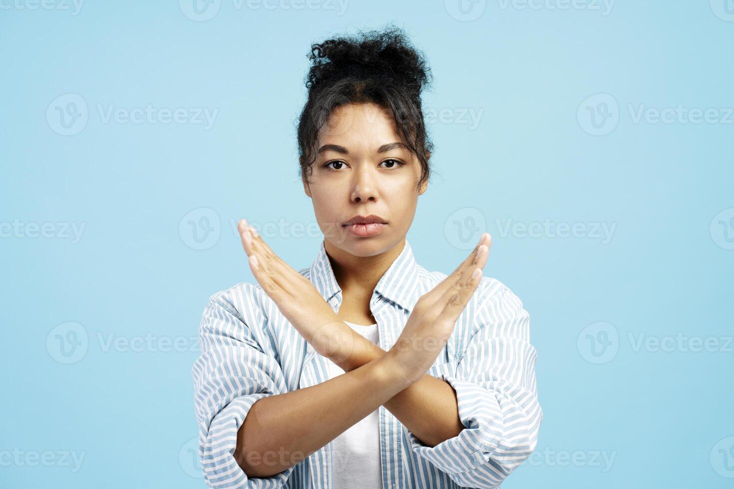 Serious young woman showing stop sign with crossed arms photo