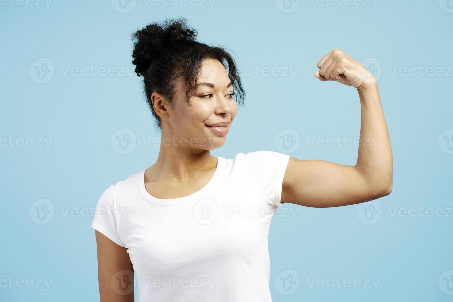 Young woman showing biceps on blue background photo