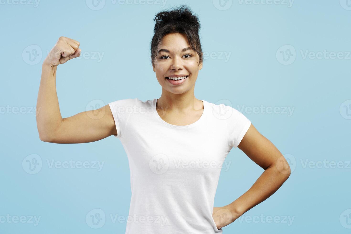 Young woman showing strength and confidence on blue background photo