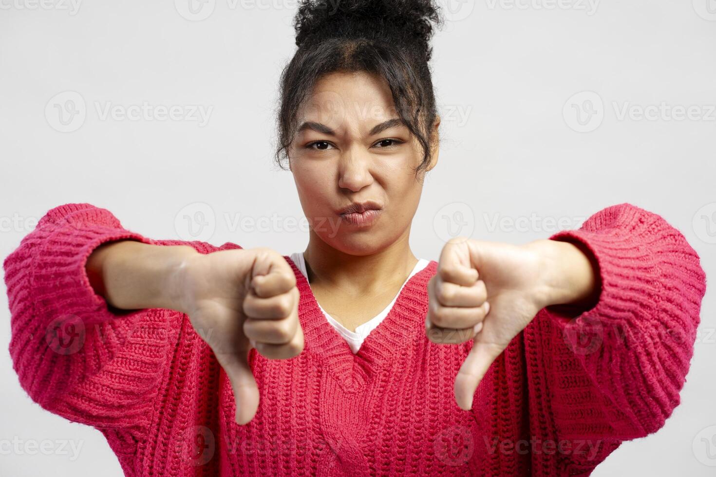 Young woman showing thumbs down gesture expressing dislike and disapproval photo