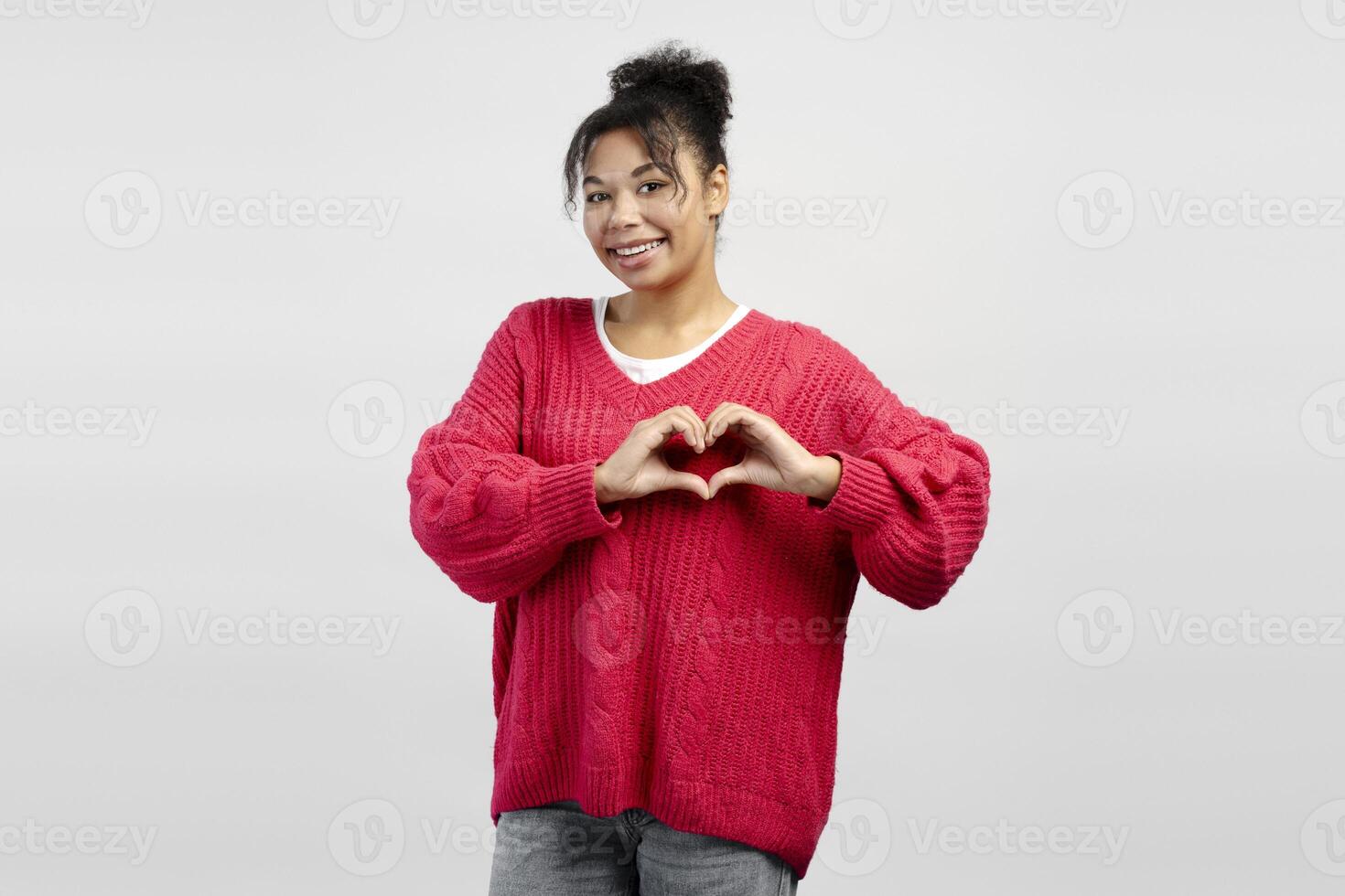 Young woman showing heart shape with hands, expressing love and affection photo