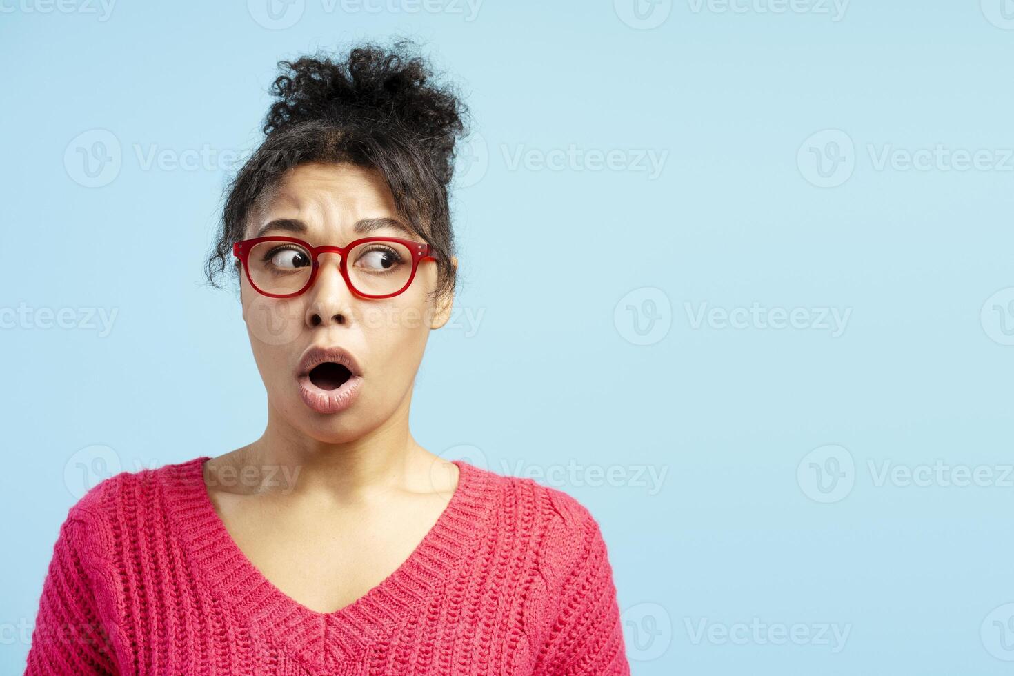 Shocked young woman looking sideways on blue background photo