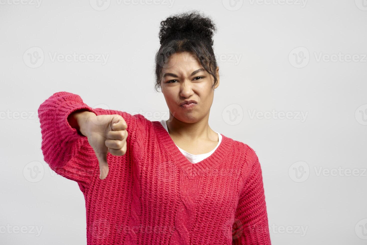 Young woman showing thumbs down gesture expressing dislike photo