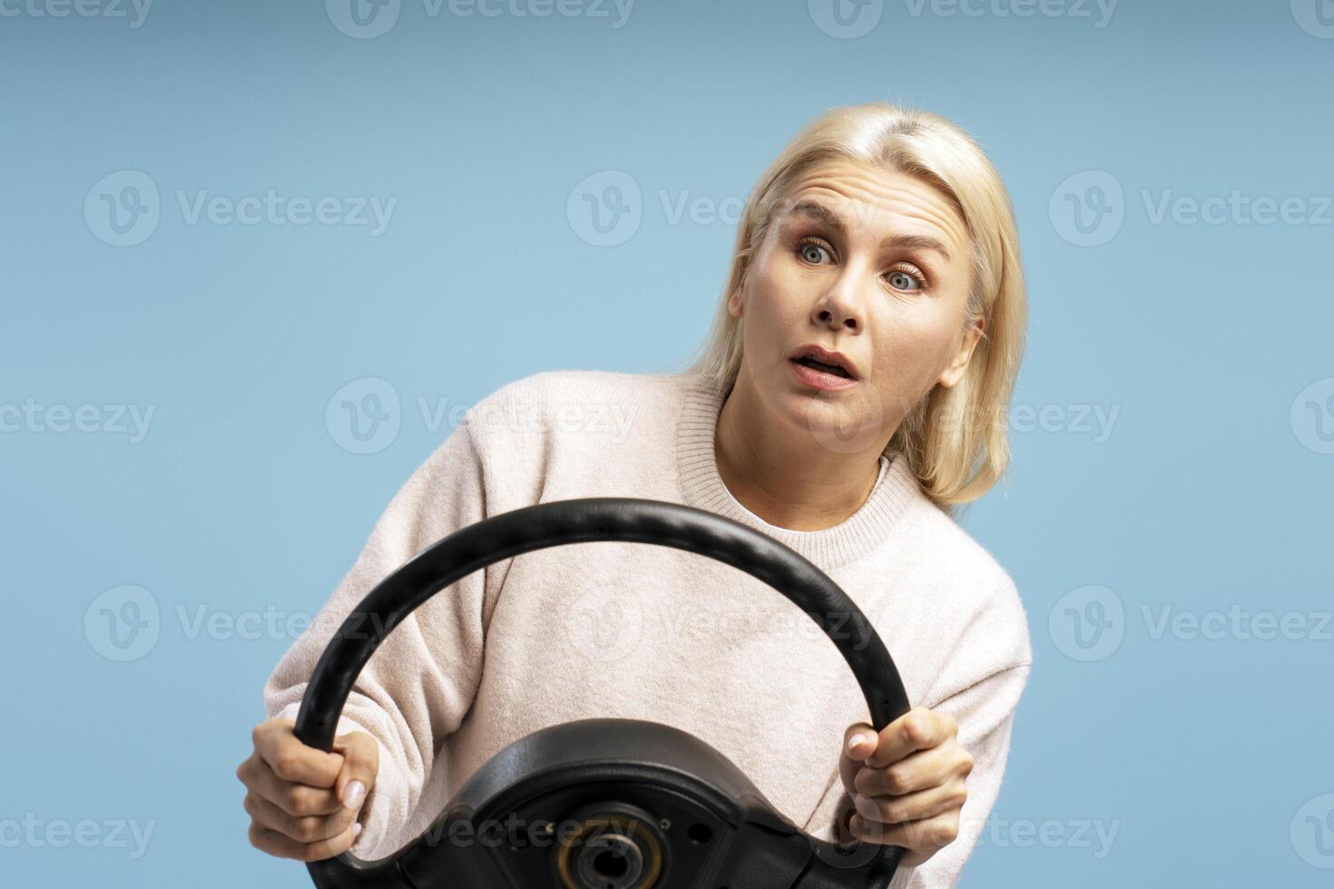 Shocked woman driving with steering wheel on blue background photo