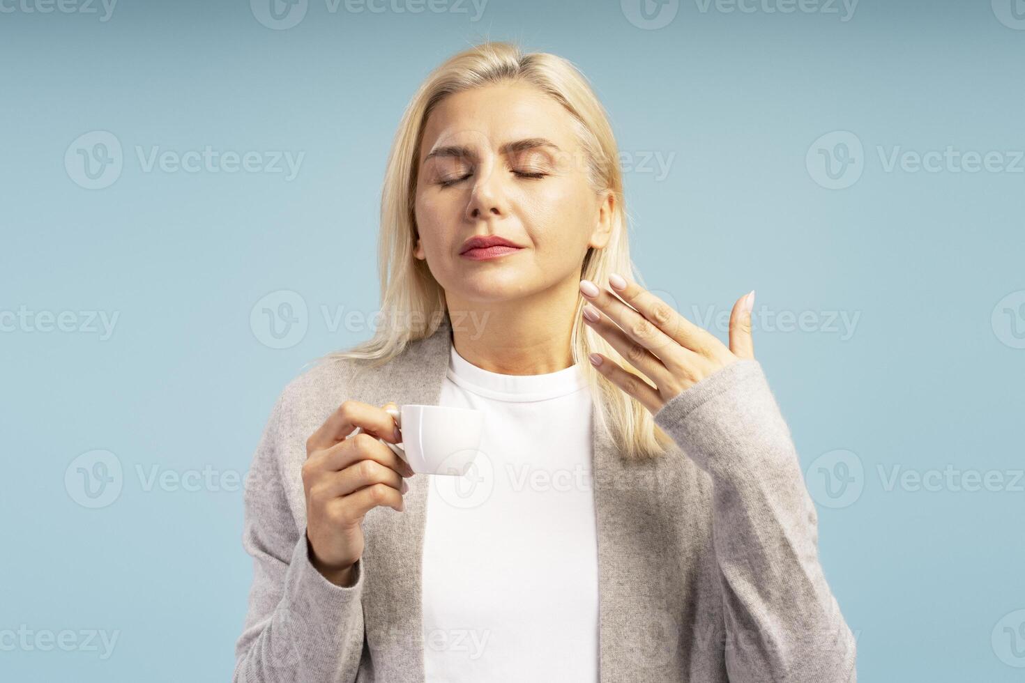 Blond woman relaxing with hot coffee on blue background photo