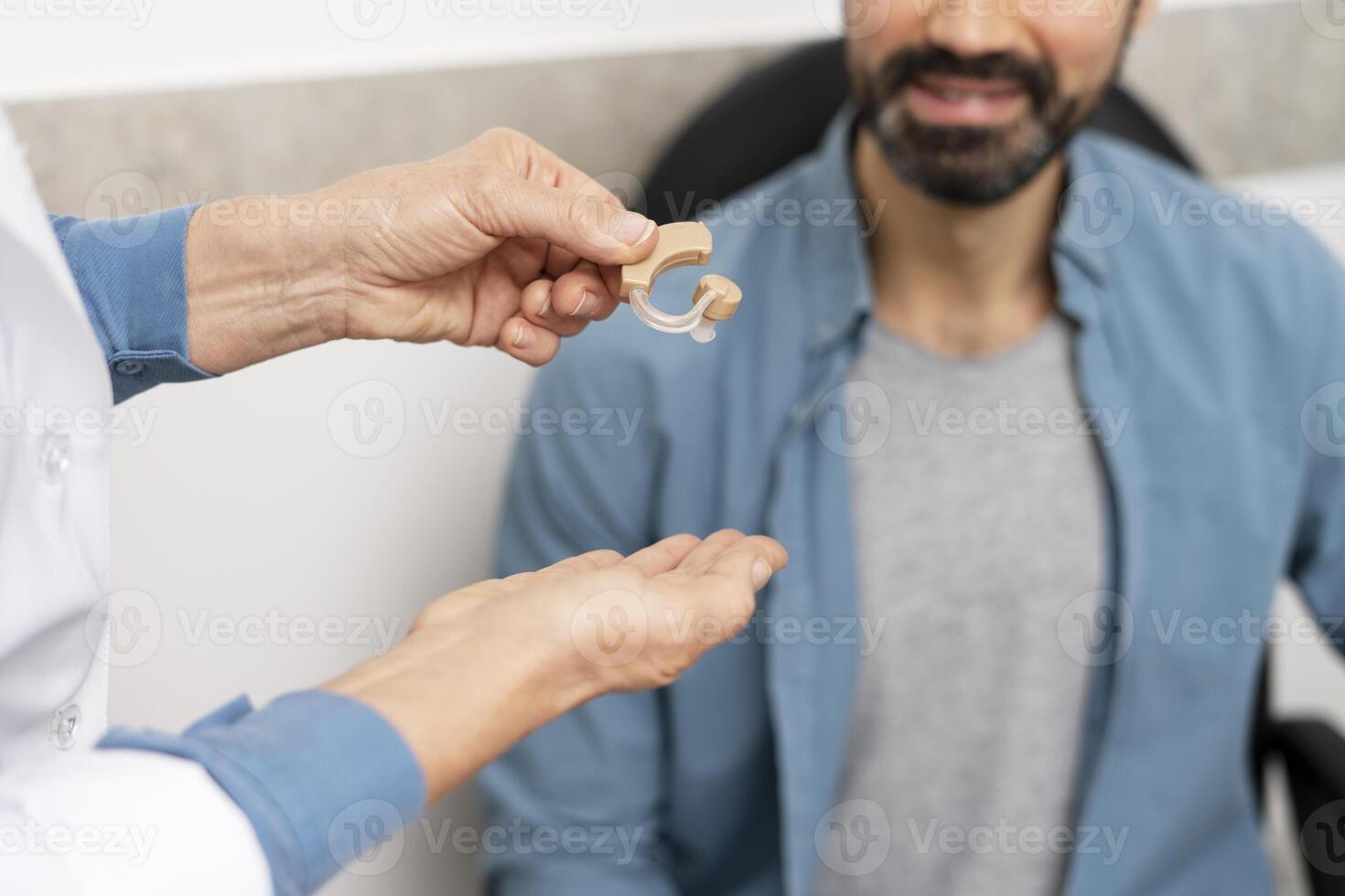 Doctor giving hearing aid to patient in medical clinic selective focus closeup photo