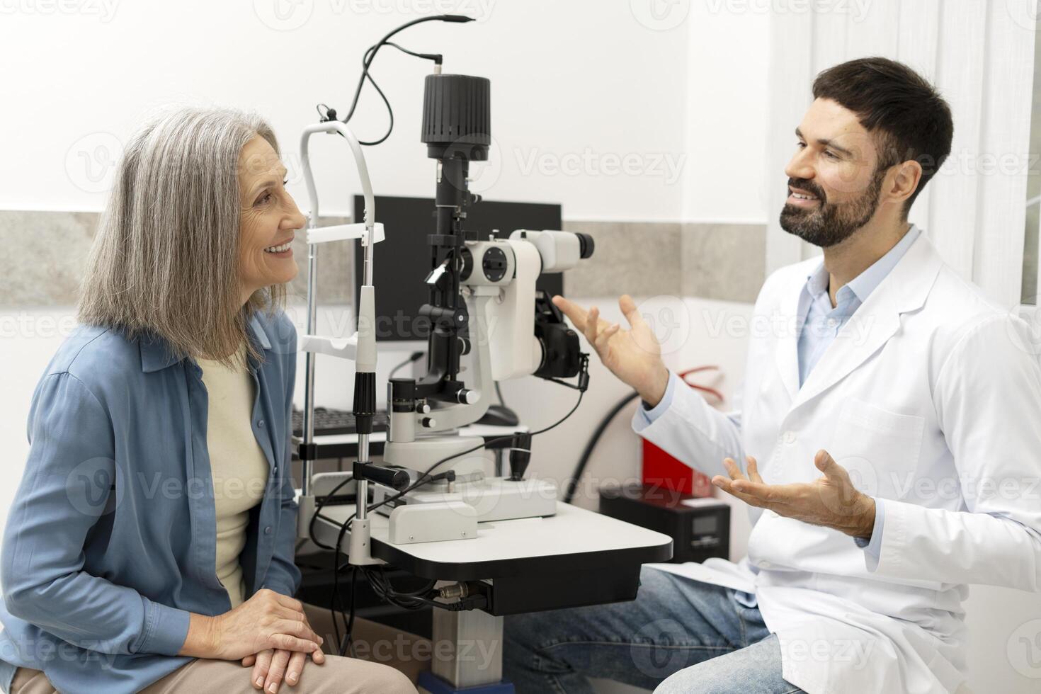 Senior woman undergoing eye exam with optometrist explaining test results photo