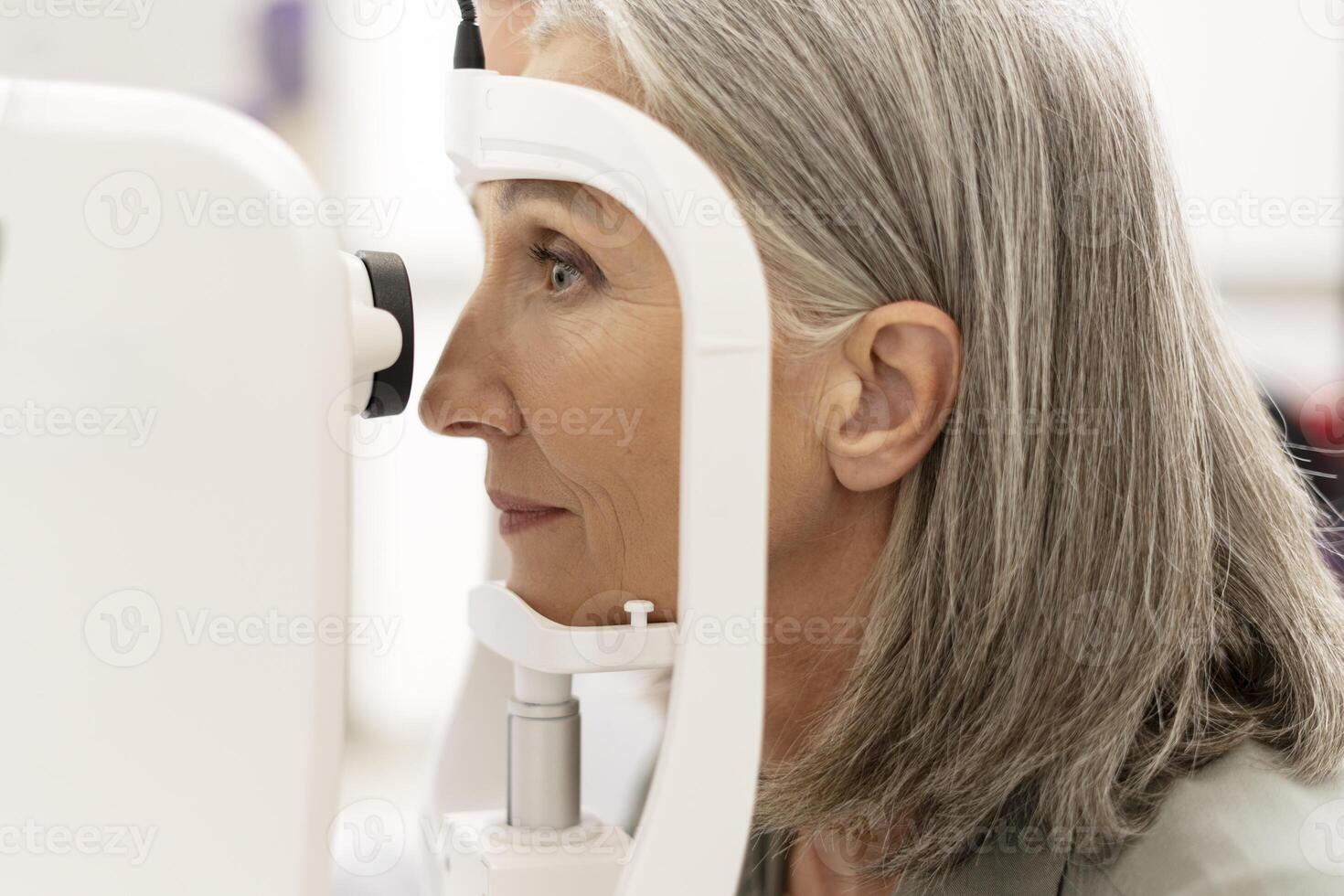 Senior woman undergoing eye exam with modern equipment photo