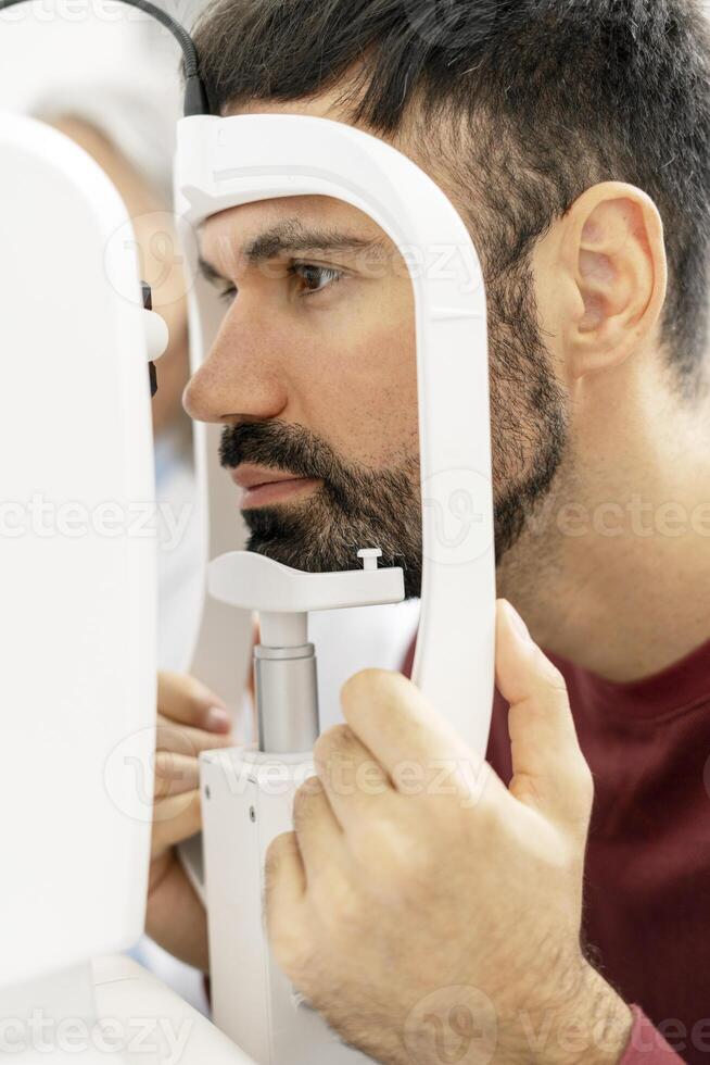 Patient undergoing eye examination with modern equipment in ophthalmology clinic photo