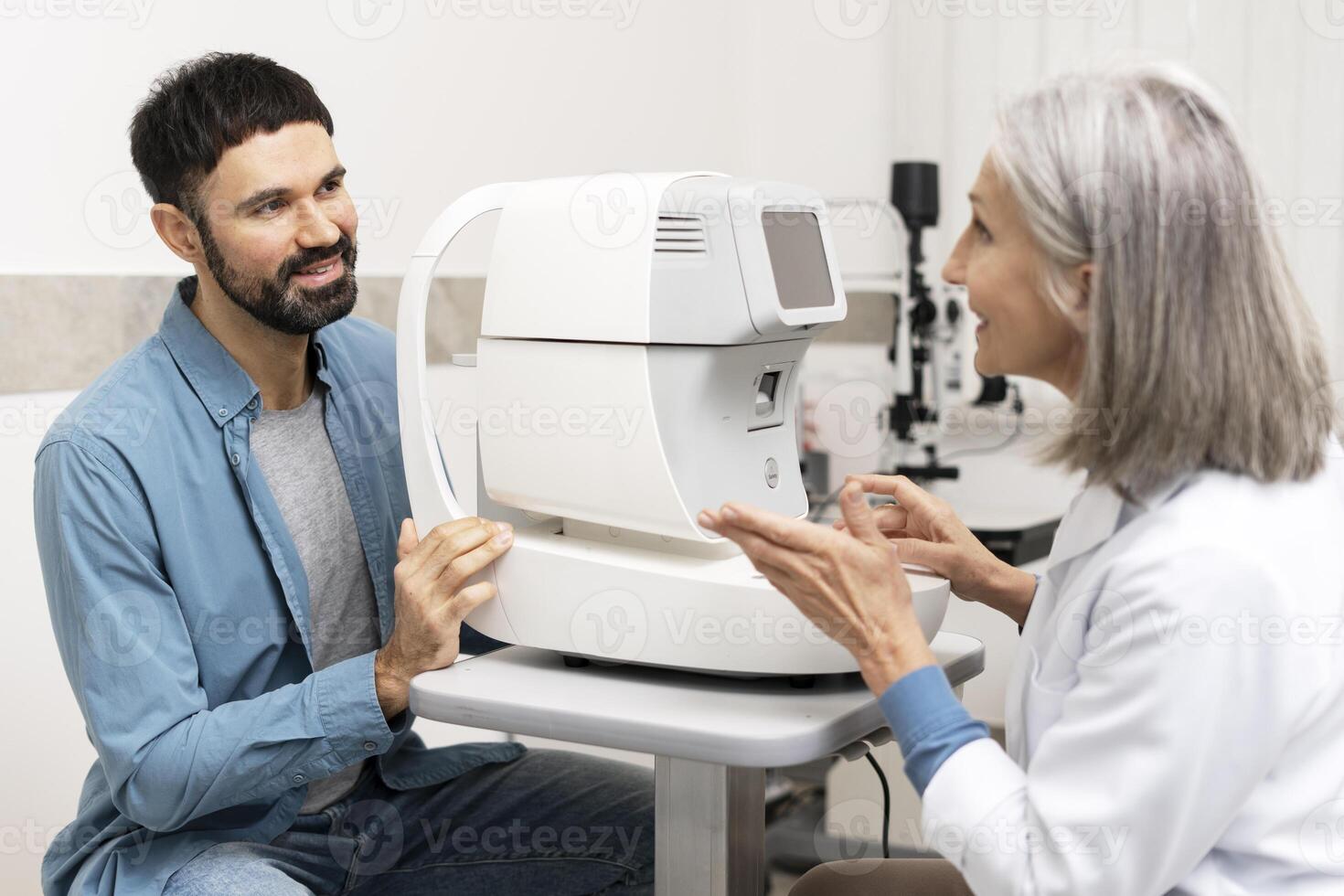 Ophthalmologist explaining autorefractor device to patient during eye exam photo