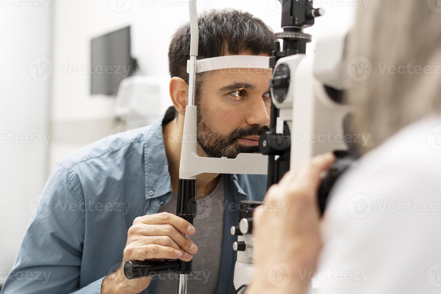 Optometrist examining patient's eyesight with slit lamp biomicroscope in ophthalmology clinic photo