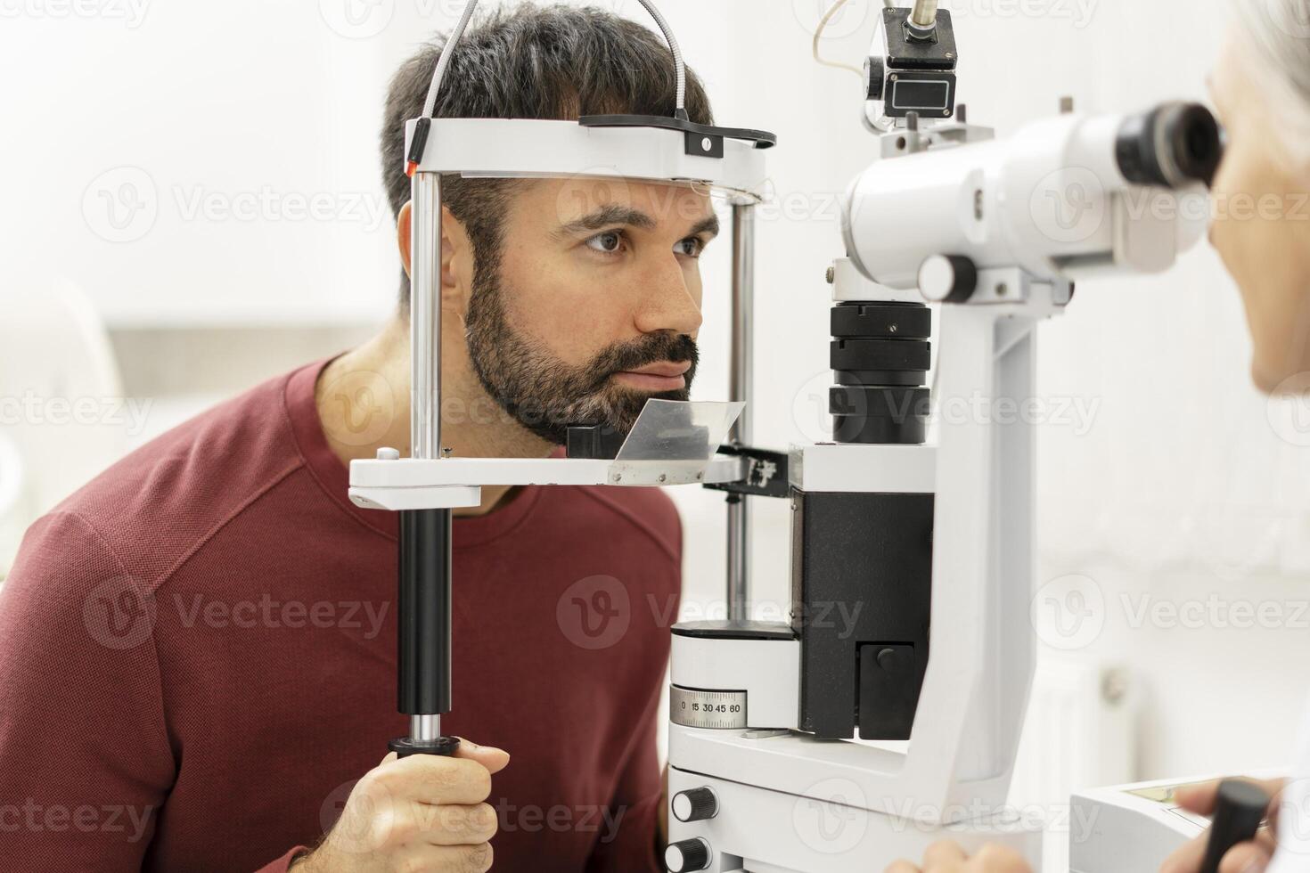Optometrist examining patient's eyesight with slit lamp biomicroscope in ophthalmology clinic photo