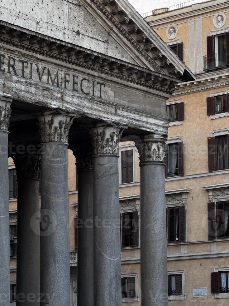 Historic columns of ancient temple stand resilient against a backdrop of elegant Roman architecture during daylight in Rome photo