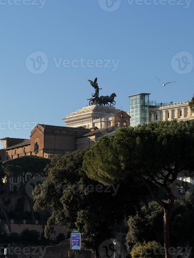 Views of historic architecture with a prominent statue atop a building in Rome during a clear day showcasing the city's rich cultural heritage photo