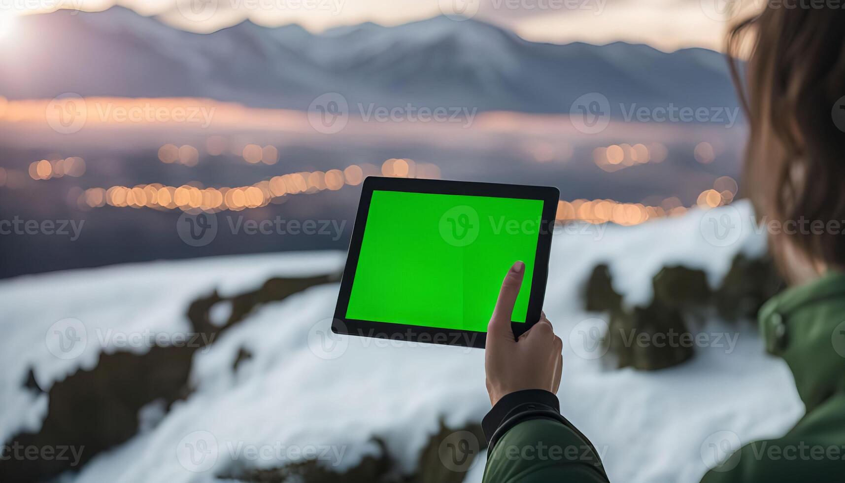 Person holding tablet with green screen in front of mountains photo