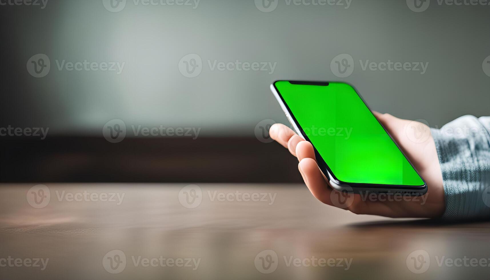Hand holding a smartphone with a green screen photo