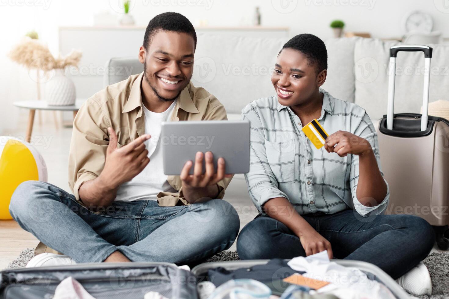Joyful African Tourists Couple Booking Tour Online With Digital Tablet And Credit Card, Browsing Internet And Purchasing Travel Tickets Together At Home. Travel Services And Applications Concept photo