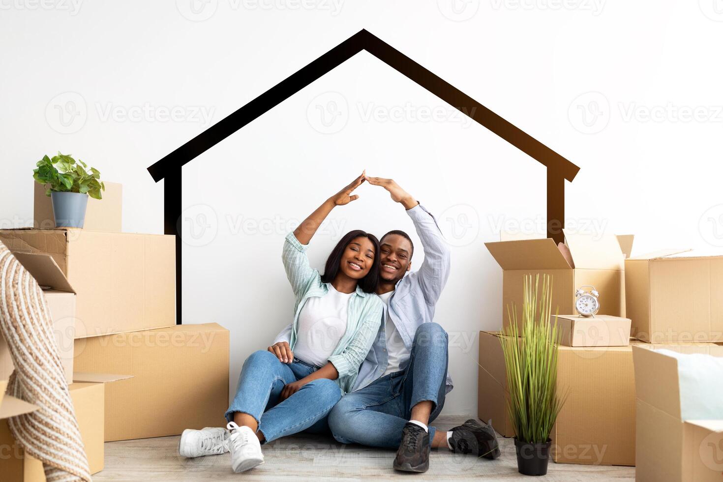 Mortgage for young families. Happy black couple moving to their own home, joining hands making symbolic house roof, sitting among cardboard boxes and smiling to camera photo