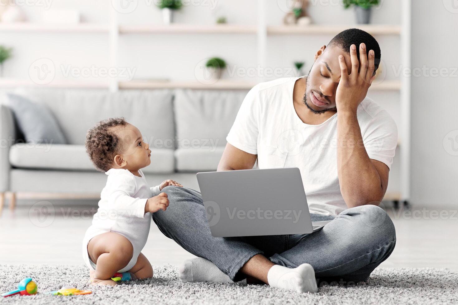 Stressed Black Man Trying To Work With Laptop At Home While Little Baby Distracting Him, Tired African American Father Suffering Difficulties With Remote Job And Paternity Leave, Free Space photo