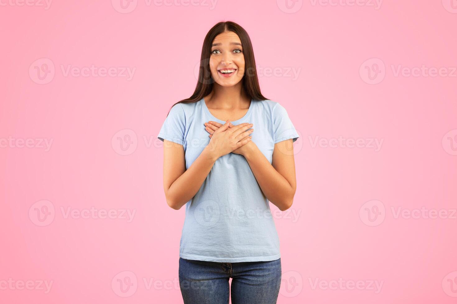 Thank You. Impressed Young Woman Keeping And Pressing Hands To Her Chest Expressing Gratitude, Touched By Compliment Posing Over Yellow Studio Background. Appreciation Concept photo