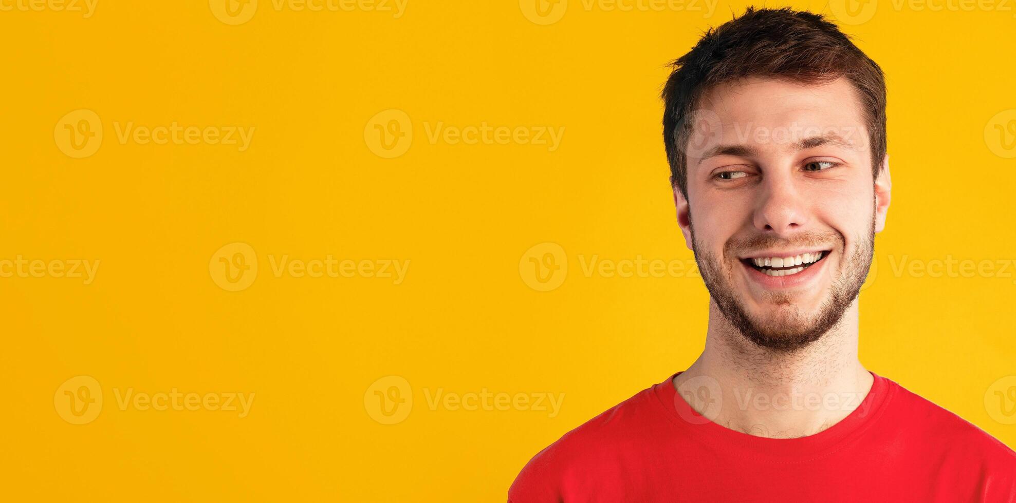 Place For Advertisement. Closeup headshot portrait of smiling young man looking away at free copy space. Unshaven guy posing isolated over blue studio background wall. Banner for commercial promotion photo