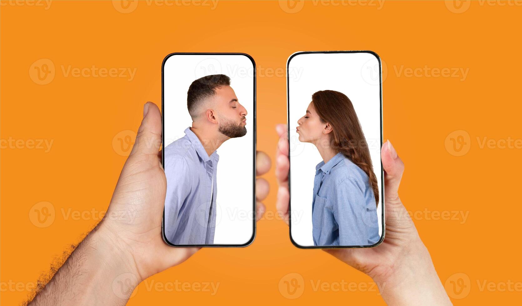 Two hands hold smartphones displaying a couple playfully kissing through chat. The bright orange background highlights their connection and affection in a modern digital setting. photo