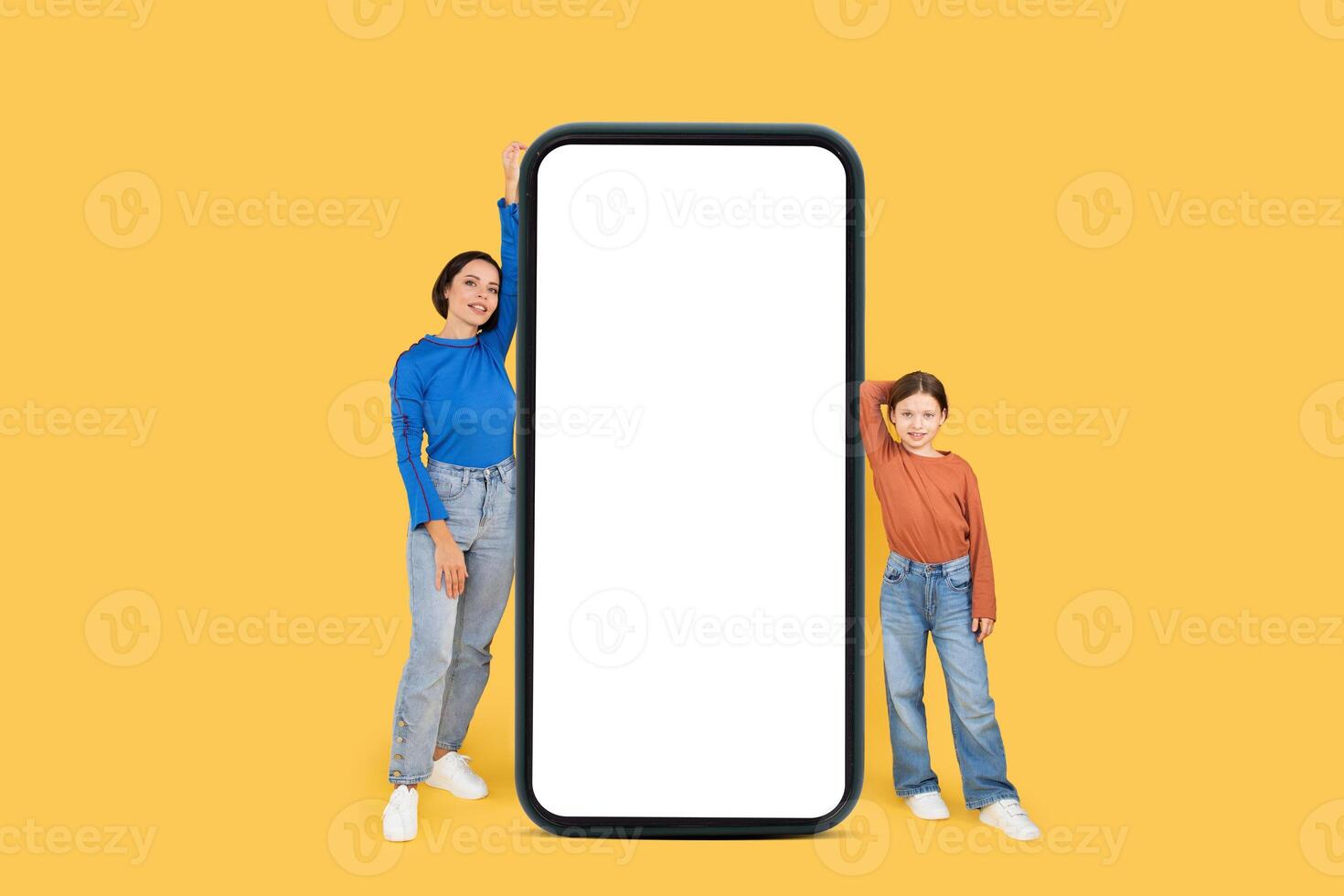A mother and her daughter share a joyful moment, standing proudly beside a large empty frame. They are dressed in colorful outfits and radiate love and bonding against a cheerful yellow background. photo