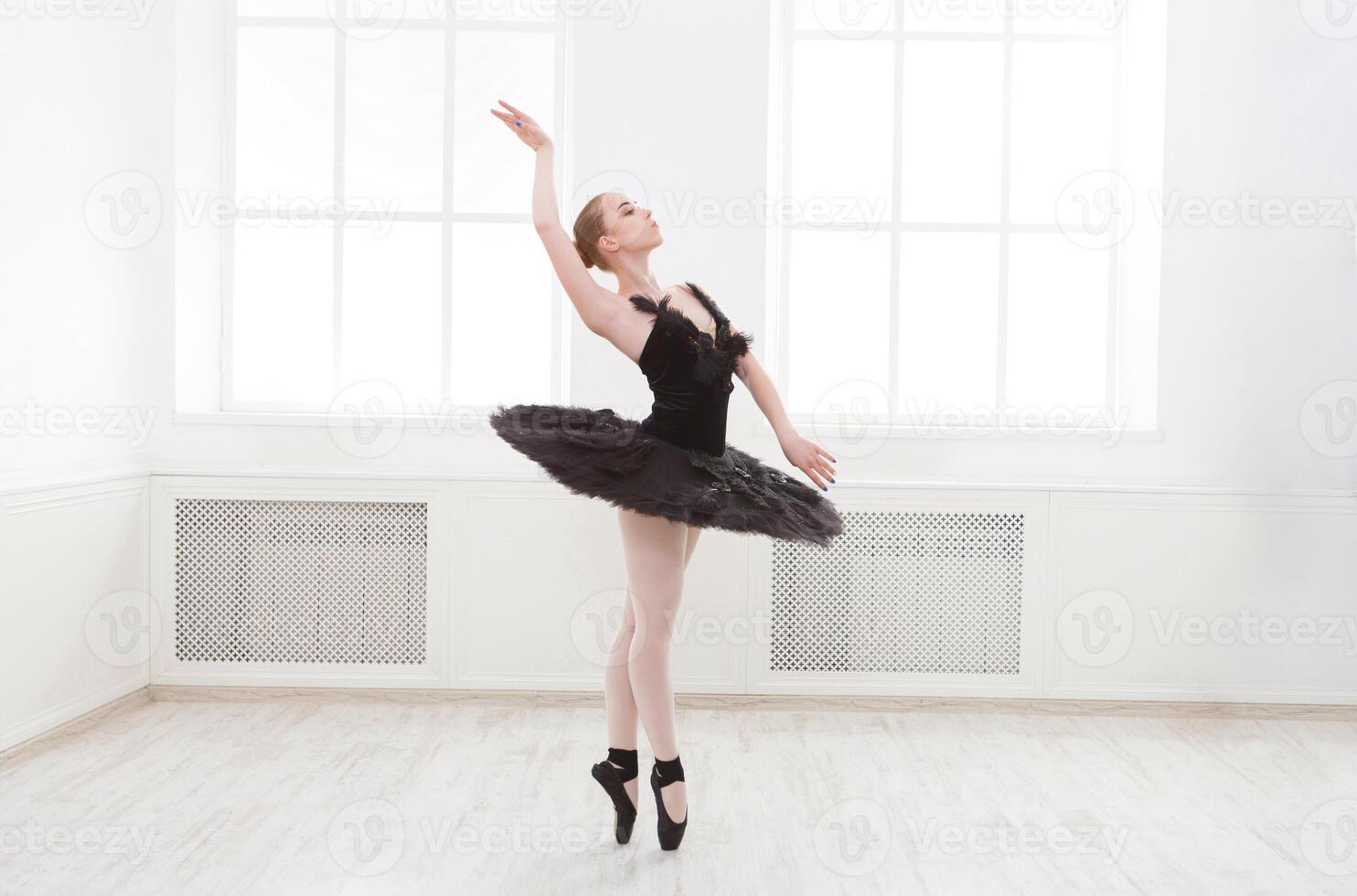 Beautiful graceful ballerina in black swan dress. Young ballet dancer practicing before performance in black tutu, classical dance studio, copy space photo