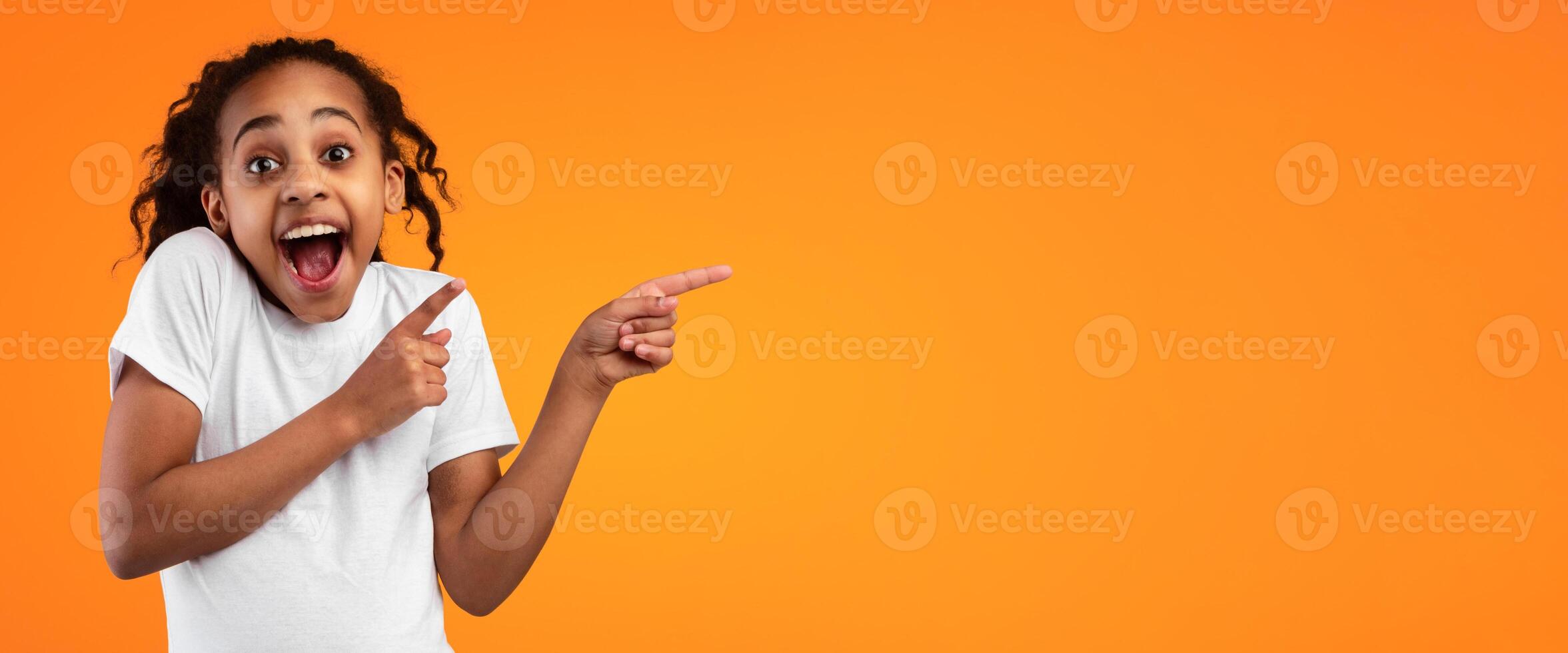Great Offer Concept. Portrait Of Excited Black Girl Pointing Two Fingers Aside At Free Copy Blank Space For Text Standing On Yellow Orange Studio Background. Look There, Panorama, Banner photo