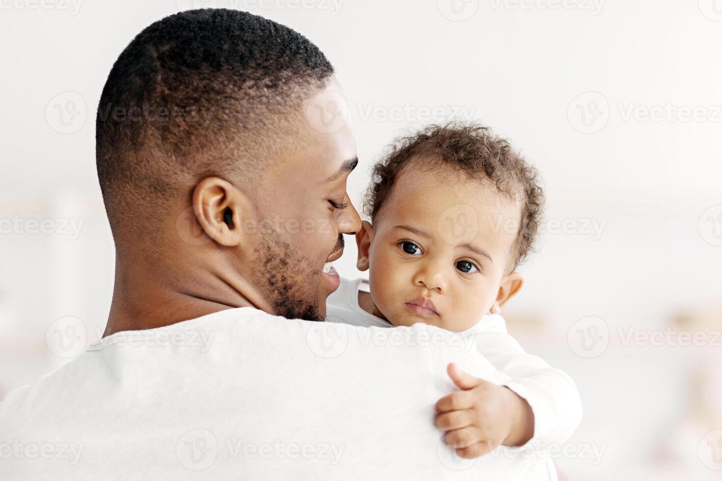 Father's love. Young afrian american dad holding his sweet infant baby in hands, closeup shot of caring black millenial dad spending time with cute adorable toddler child at home, copy space photo
