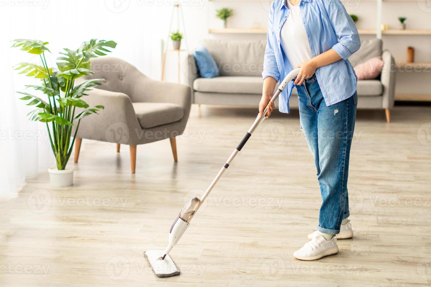 Homework Cleaning Routine. Cheerful casual lady washing hardwood laminate flooring using water spray mop pad, smiling and looking at camera. Blurred Background, Free Copy Space, Modern Interior photo