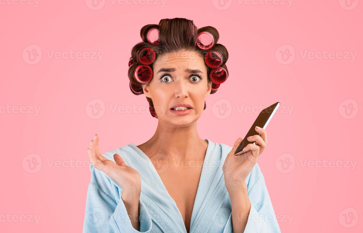 Oops. Embarassed Housewife Holding Mobile Phone Looking At Camera In Confusion Posing On Yellow Studio Background. photo