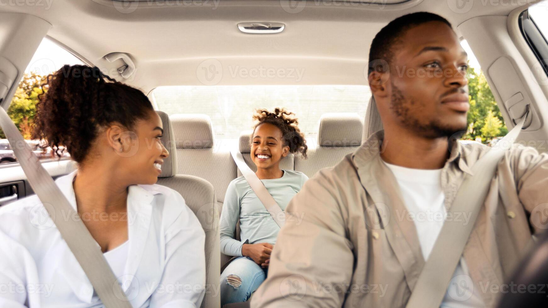 Car Leasing. Happy African American Family Driving New Automobile Enjoying Road Trip On Summer Vacation. Parents And Kid Riding Traveling By Auto. Selective Focus On Daughter photo